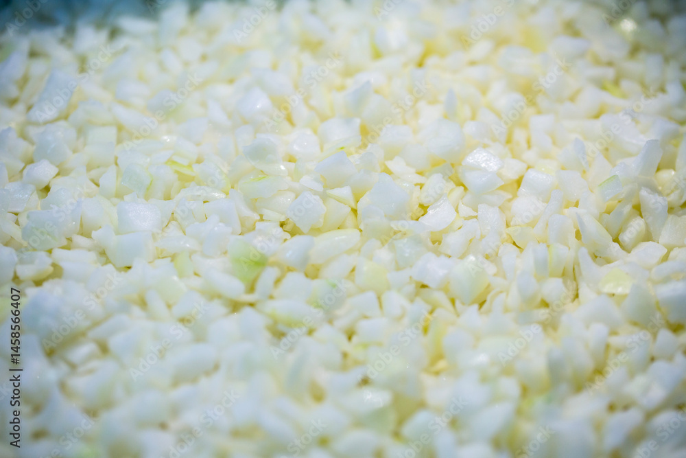 Close-up of shock-frozen chopped onion pieces with a thin ice coating. Are prepared for retail packaging to ensure extended shelf life in supermarkets and maintain perishable harvest quality.