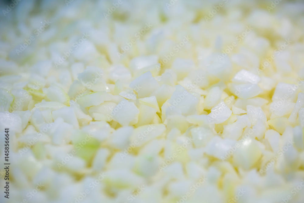 Close-up of shock-frozen chopped onion pieces with a thin ice coating. Are prepared for retail packaging to ensure extended shelf life in supermarkets and maintain perishable harvest quality.