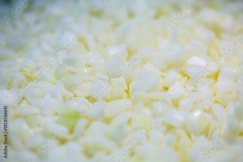 Obraz na płótnie Close-up of shock-frozen chopped onion pieces with a thin ice coating. Are prepared for retail packaging to ensure extended shelf life in supermarkets and maintain perishable harvest quality. w salonie
