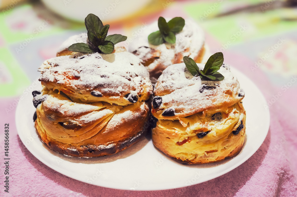 Three delicious cruffins dusted with powdered sugar and garnished with mint leaves on a plate.