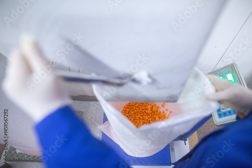 Obraz na płótnie Bright diced carrot pieces, after passing through the shock-freezing chamber, are packaged in polyethylene bags by weight for shipment to customers. Рrepared for retail to ensure extended shelf life. w salonie