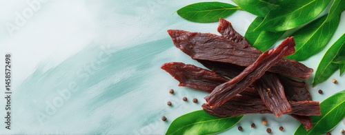 Obraz na płótnie Savory Jerky Strips Surrounded by Fresh Green Leaves and Spices w salonie