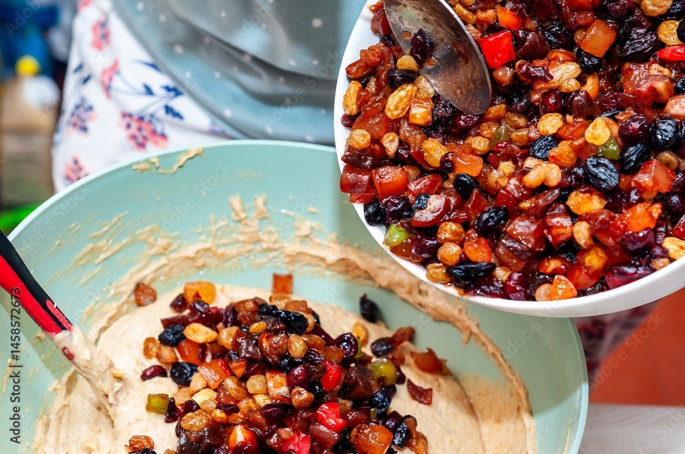 Adding candied fruit to cake batter, preparing a delicious, homemade treat in the kitchen.