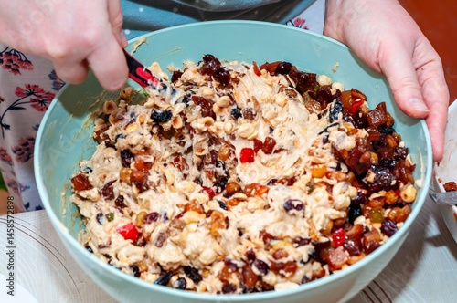 Obraz na płótnie A close-up shot captures hands mixing a bowl of fruitcake batter with a spoon. w salonie