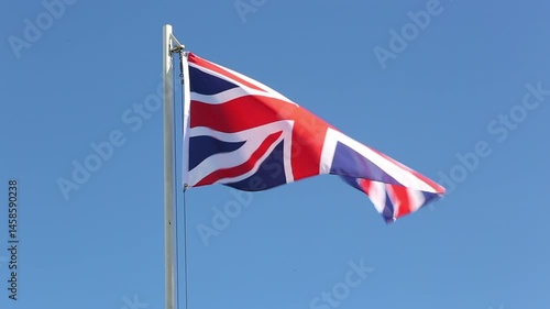 Flag of UK on a flagpole in front of blue sky