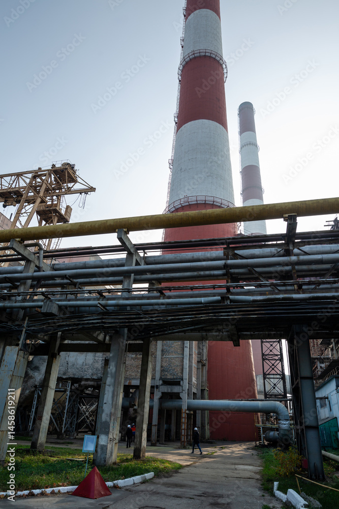 A massive gas exhaust system at a high-capacity thermal power plant. Towering red-and-white chimneys exceed 150 meters in height, facilitating emissions management and industrial air circulation.