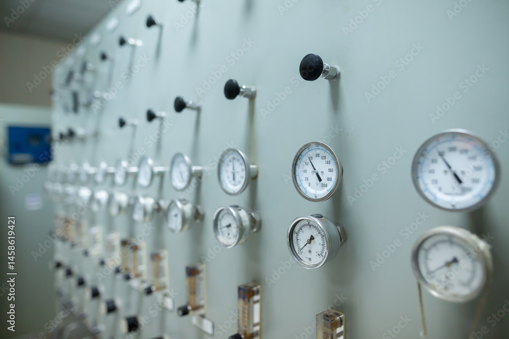 Control panel with multiple pressure gauges and adjustment knobs used for regulating fluid or gas pressure in an industrial system. The gauges display various pressure levels