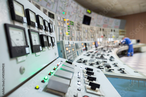 Control room featuring multiple control panels with gauges, switches, and indicator lights. A worker monitoring the system, ensuring proper operation and adjustments in an industrial environment