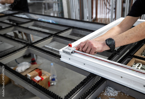Obraz na płótnie Production area for metal-plastic or PVC windows, commonly known as vinyl windows. A worker is installing locks onto a window frame using red clamps and a fastening tool. w salonie