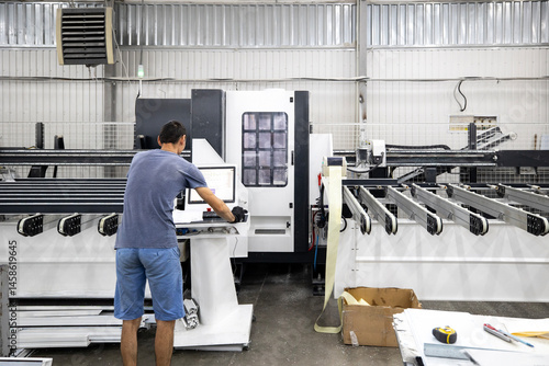Obraz na płótnie Production area for metal-plastic or PVC windows, commonly known as vinyl windows. A worker operates a machine, cutting linear profiles to precise measurements. w salonie