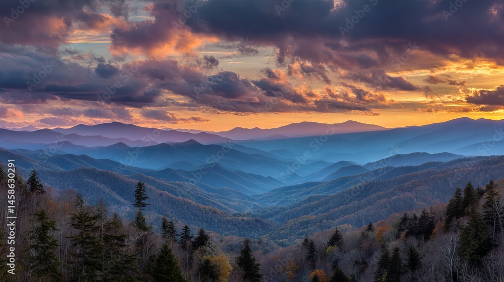 Obraz premium Colorful sunset over smoky mountain range with glowing clouds and layered forest landscape