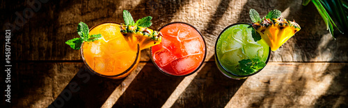 Top-down view of three colorful tropical cocktails on a rustic wooden bar, garnished with fresh pineapple, mint, and citrus slices, warm golden sunlight casting soft shadows, high-end commercial style