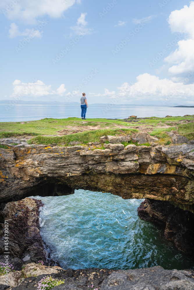 Obraz premium Beeindruckende Fairy Bridges mit Tullan Strand im Hintergrund und eine Frau die darüber geht