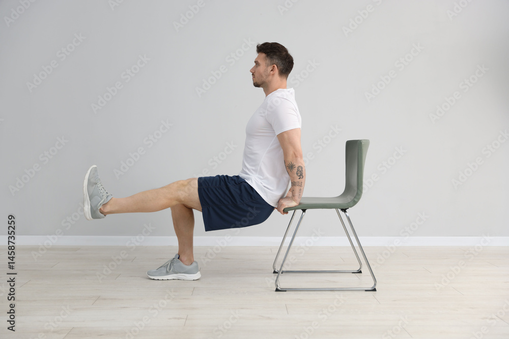 Fototapeta premium Handsome man exercising with chair at home