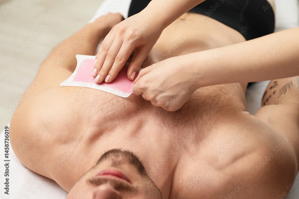 Fototapeta premium Young man undergoing wax epilation in salon, closeup