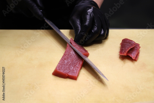 chef especialista en sushi cortando lonchas de atún rojo crudo para hacer sushi y comida asiática