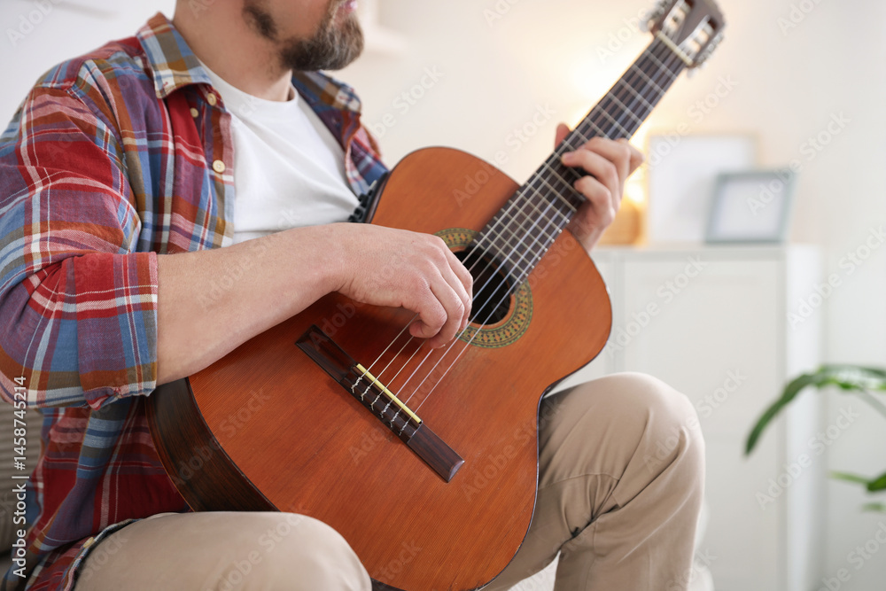 Obraz premium Man playing acoustic guitar at home, closeup