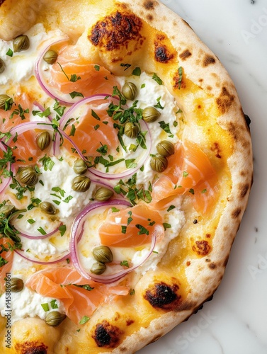 Close-up of a flatbread pizza on a white marble surface. the pizza has a golden-brown crust and is topped with a generous amount of cream cheese, sliced red onions, and smoked salmon.
