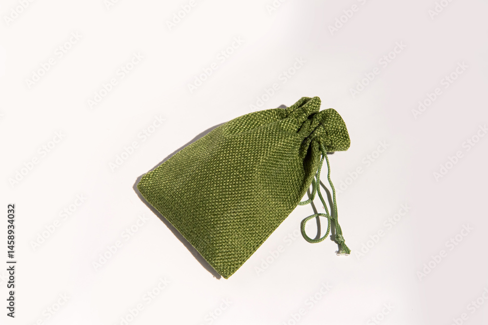 Green fabric drawstring bag on white background: elegant textured storage pouch