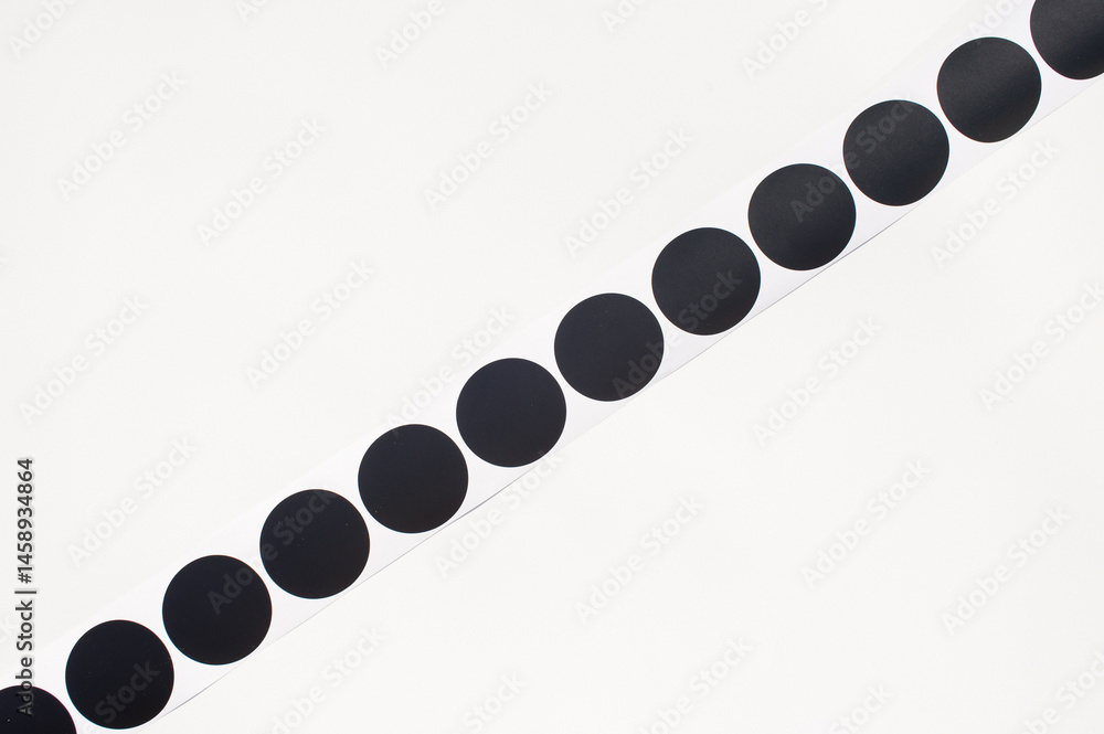 Black circle stickers on a roll against white background