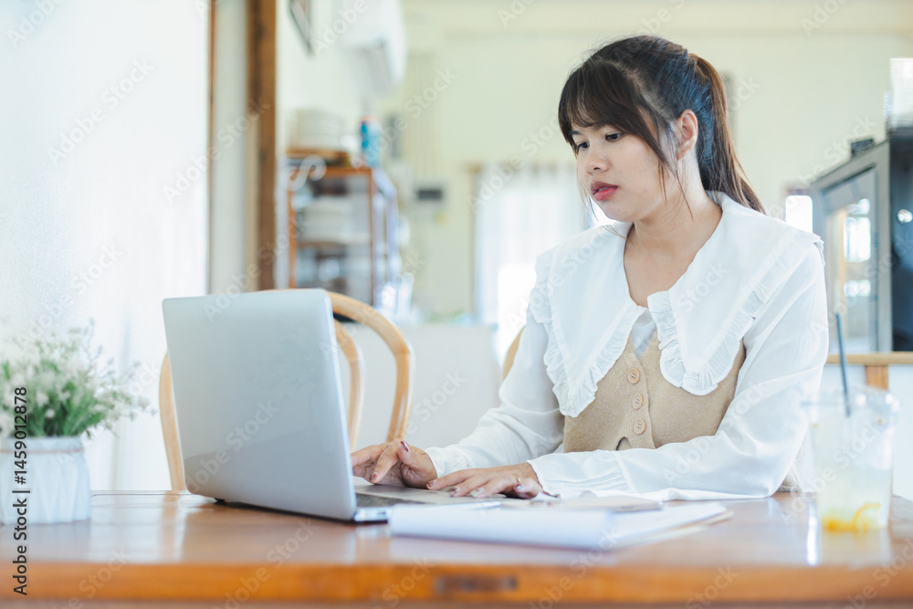 Asian woman is working remotely as digital nomad focused on her laptop in cozy home setting with natural light and calm atmosphere Asian woman is working remotely as digital nomad focused on her laptop in cozy home setting with natural light and calm atmosphere