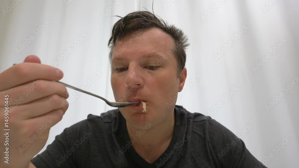 Man eats salad fresh with spoon sitting in kitchen. Man eats greens vegan food. Protein natural. Slow motion Man eats salad fresh with spoon sitting in kitchen. Man eats greens vegan food. Protein natural. Slow motion