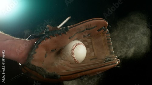 Super slow motion of hand in brown leather baseball glove caught ball isolated on black background . Filmed on high speed cinematic camera