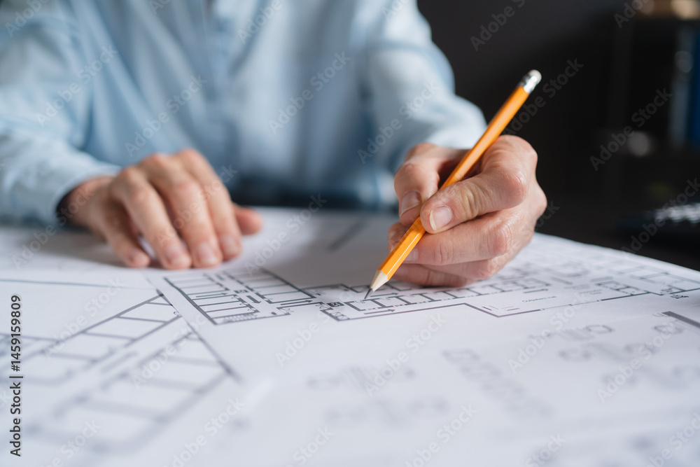 Close up of female architect sitting at her office desk and working with blueprints cadastral maps city plans. Mature Caucasian woman studying information and developing a new architectural project Close up of female architect sitting at her office desk and working with blueprints cadastral maps city plans. Mature Caucasian woman studying information and developing a new architectural project