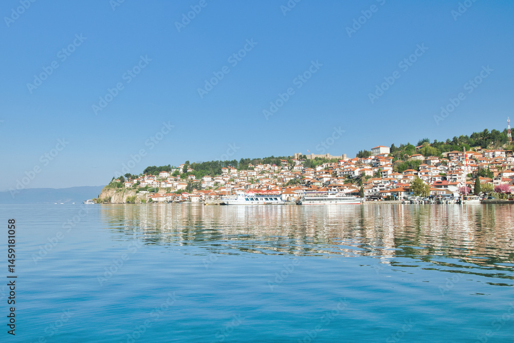 Fototapeta premium Lake Ohrid, North Macedonia, April 13 2024. Mountain range and peninsula in distance. Ohrid Lake, Macedonia, Europe. The clear mesmerizing waters of lake Ohrid with a beautiful view. 
