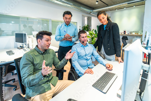 Obraz na płótnie Business team collaborating on computer project with disabled colleague in wheelchair w salonie