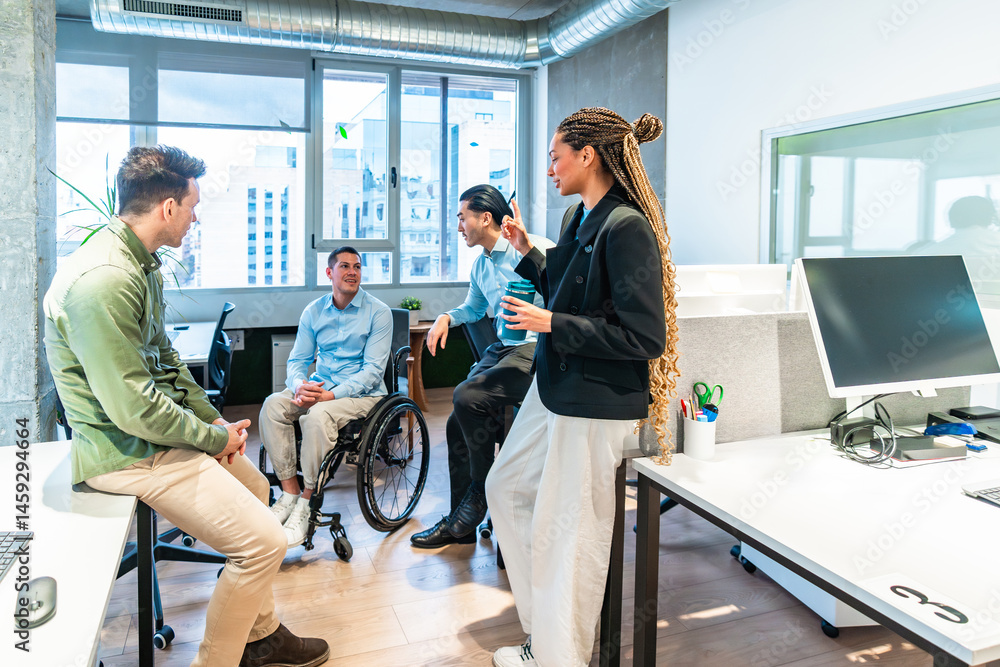 Diverse business team discussing in modern office with disabled colleague in wheelchair