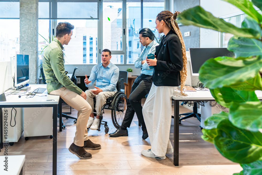 Diverse business team discussing in modern office with disabled colleague in wheelchair