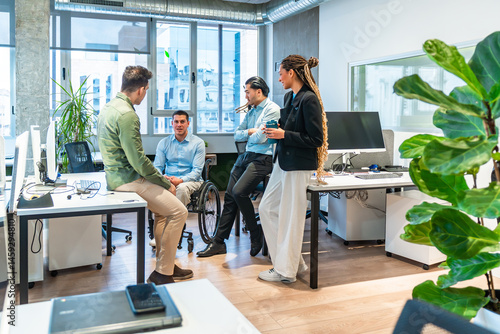 Diverse business team discussing in modern office with disabled colleague