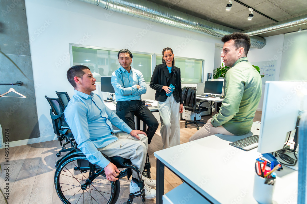 Diverse business team collaborating in modern office with disabled colleague in wheelchair
