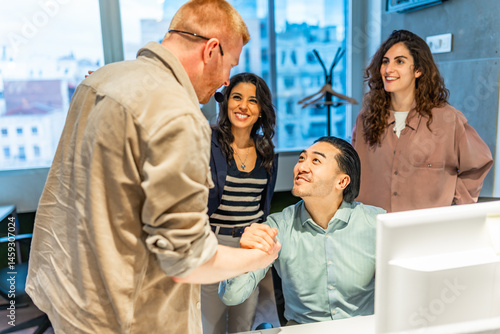 Managers shaking hands congratulating employee during a business meeting
