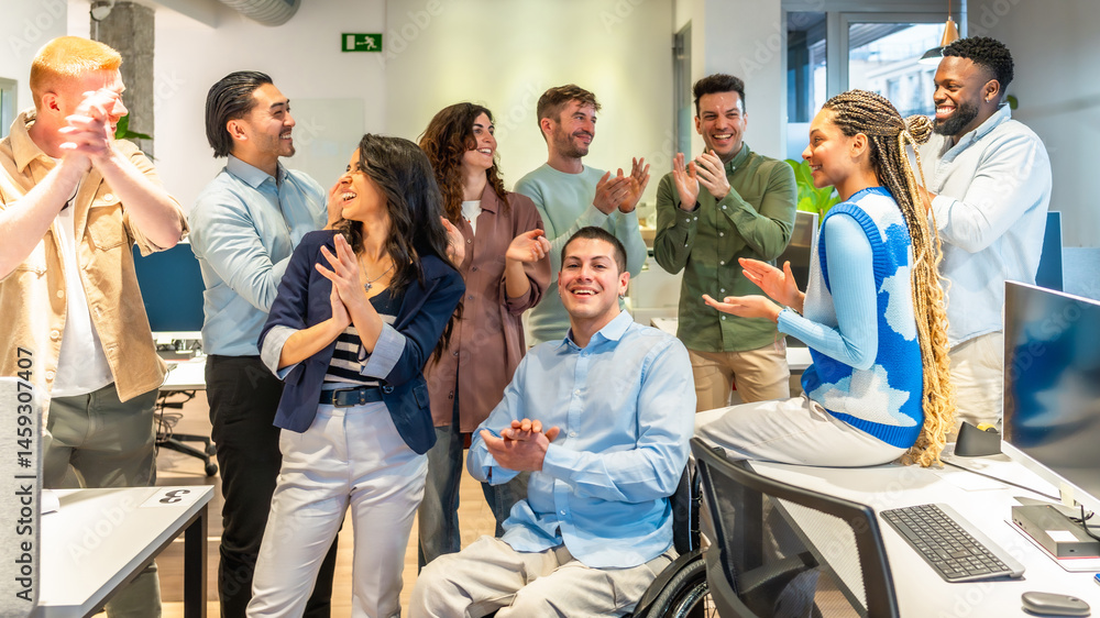 Diverse business team applauding their colleague in wheelchair in modern office