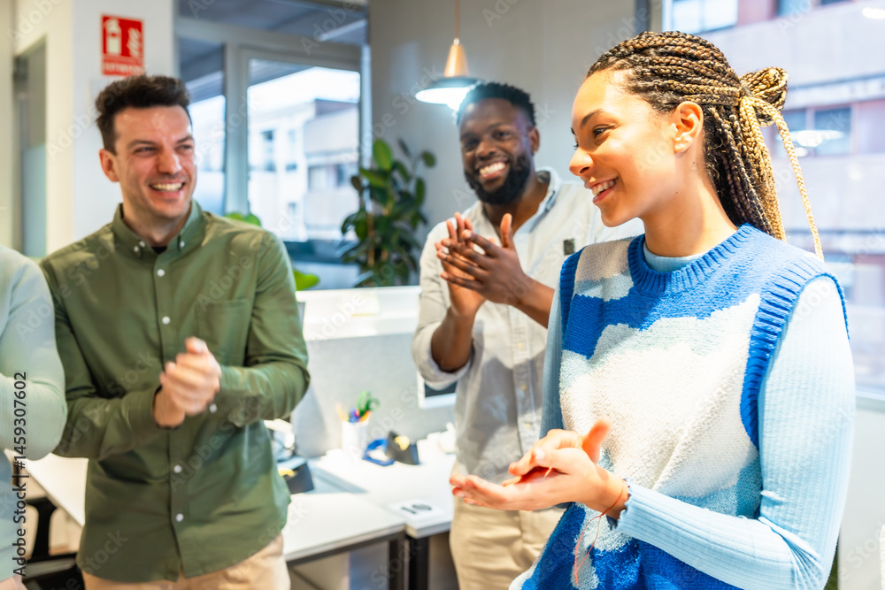 Happy business team applauding a female colleague in modern office