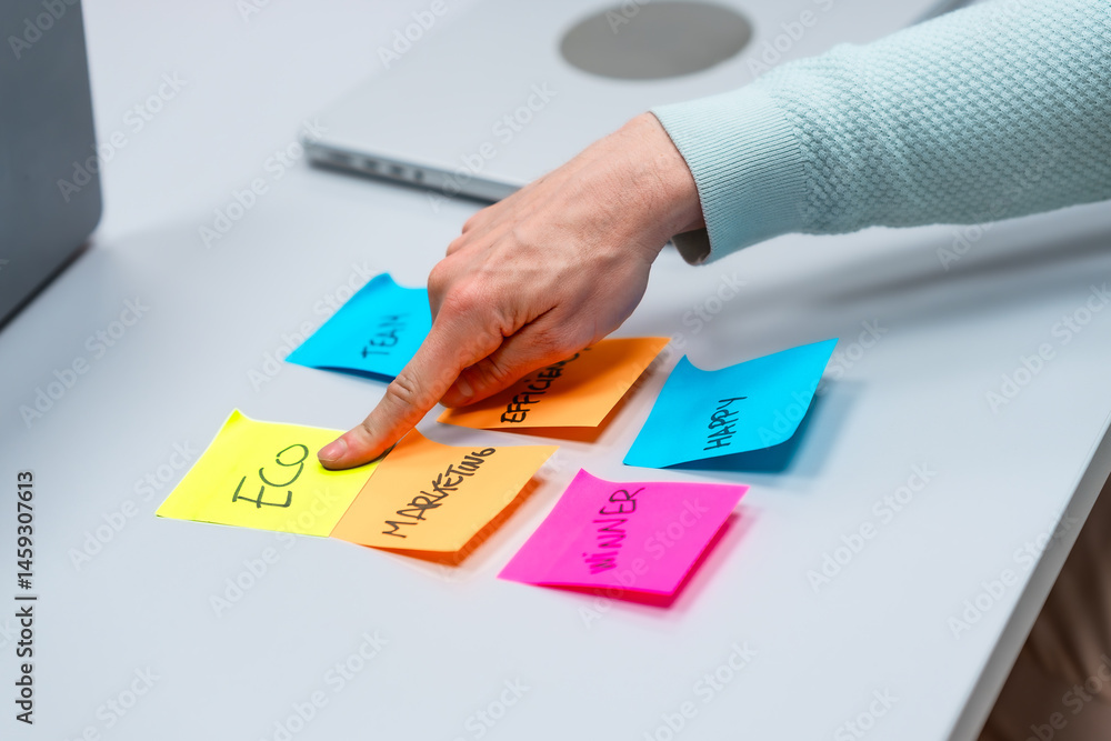 Manager organizing marketing strategy with adhesive notes on white table