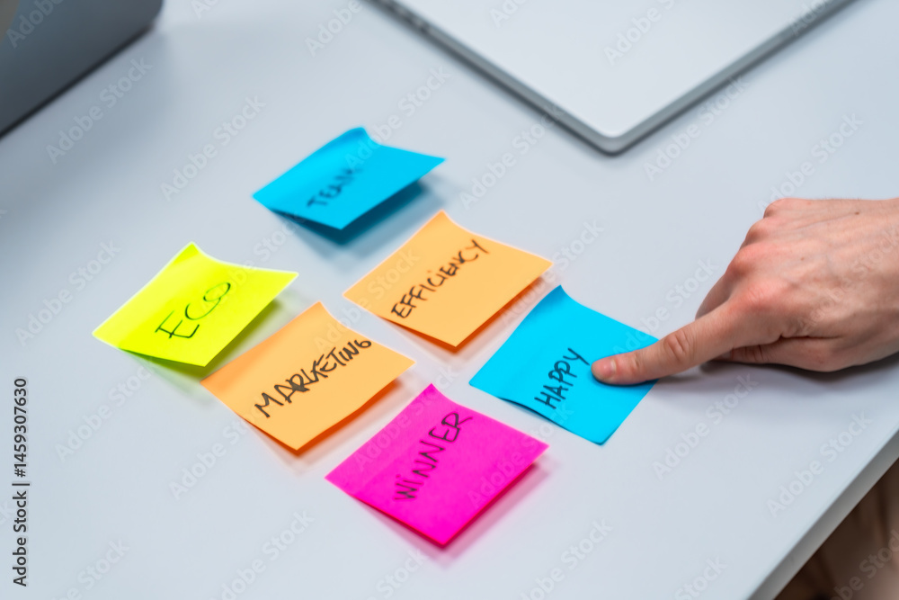 Manager choosing happy between eco, marketing, team, efficiency and winner sticky notes