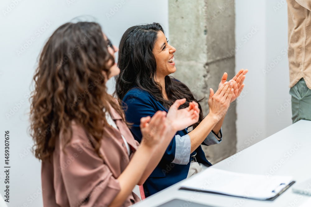 Enthusiastic businesswomen clapping hands during a meeting