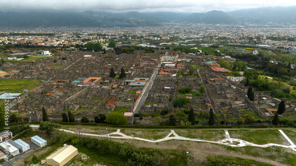 Aerial view of the ruins and remains in the archaeological park of Pompeii, located in the province of Naples, Campania, Italy. It was an ancient Roman town. In background there is the modern city.