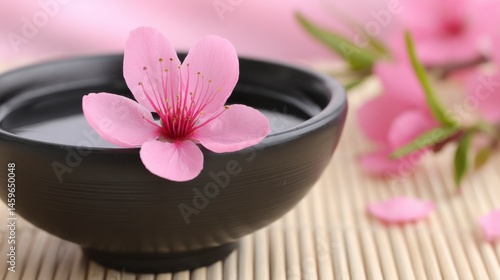 Wallpaper Mural Delicate Pink Cherry Blossom Petal Floating on Water in Black Bowl Surrounded by Soft Fabric and Bamboo Mat Torontodigital.ca