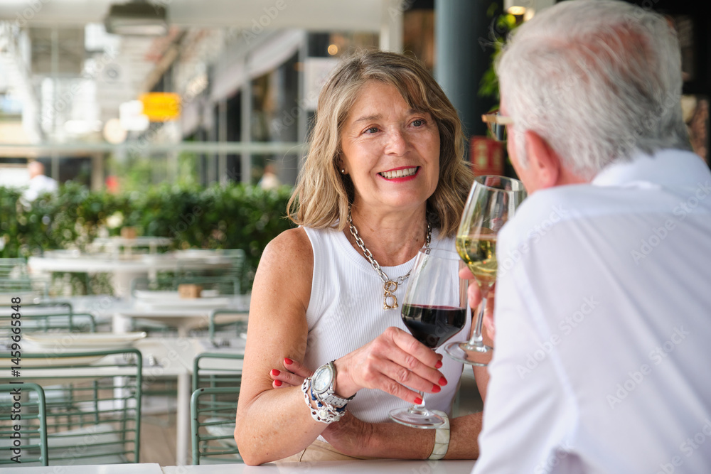 Happy mature couple toasting with wine glasses at a restaurant, celebrating their love and enjoying a romantic moment together