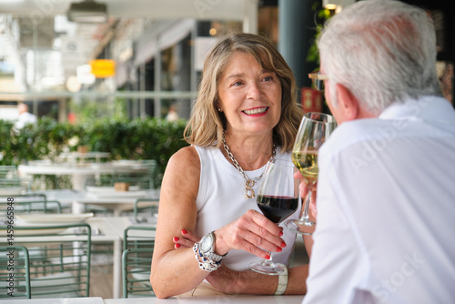 Obraz na płótnie Happy mature couple toasting with wine glasses at a restaurant, celebrating their love and enjoying a romantic moment together w salonie