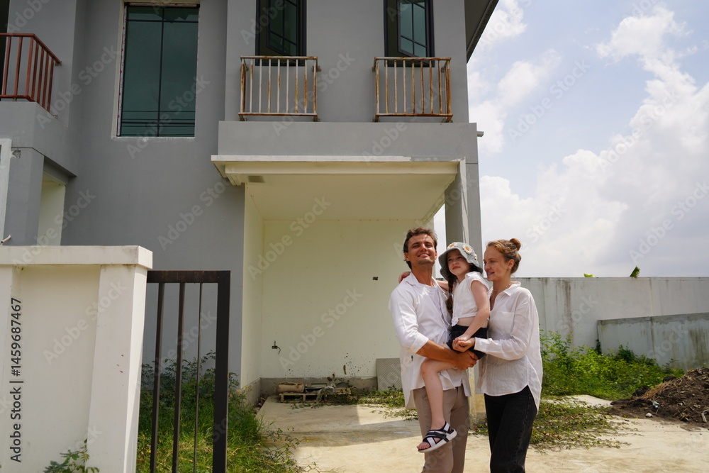Caucasian family father holding seven year old daughter with mother standing together buying a new house in a housing project planning finance insurance home loan to build a family in the future