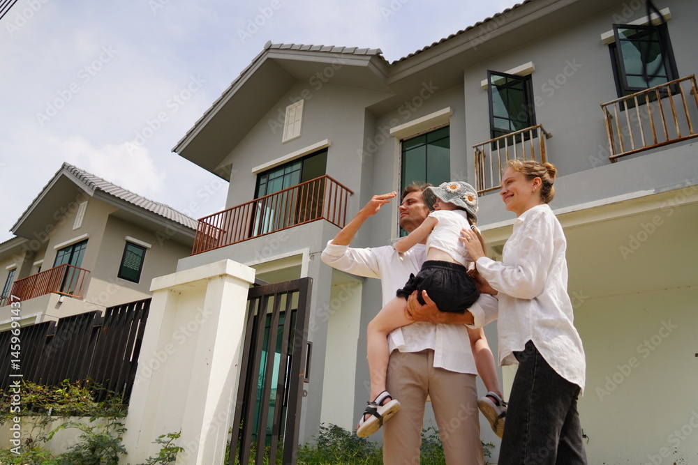 Caucasian family father holding seven year old daughter with mother standing together buying a new house in a housing project planning finance insurance home loan to build a family in the future