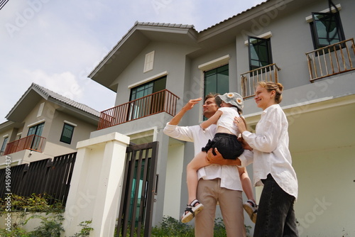 Obraz na płótnie Caucasian family father holding seven year old daughter with mother standing together buying a new house in a housing project planning finance insurance home loan to build a family in the future w salonie