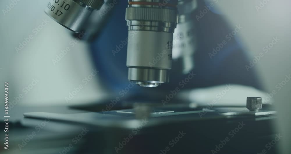 Close-up of biologist gloved hands using microscope in sterile laboratory. Vibrant blue gloves highlight precise scientific work against monochromatic lab backdrop Close-up of biologist gloved hands using microscope in sterile laboratory. Vibrant blue gloves highlight precise scientific work against monochromatic lab backdrop