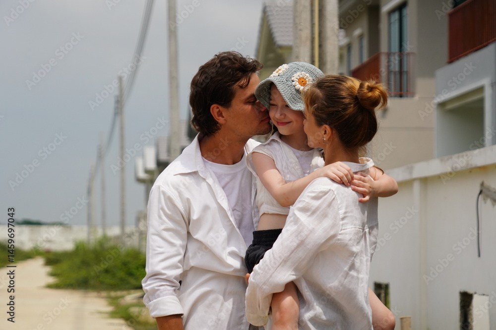 Caucasian family father holding seven year old daughter with mother standing together happily kissing cheek of three new children in housing project planning finance insurance home loan to build futur