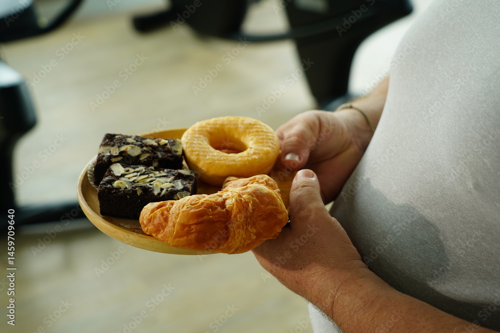 Fat man holding a tray of breakfast bread, brownies, donuts, croissants with flour and sugar.